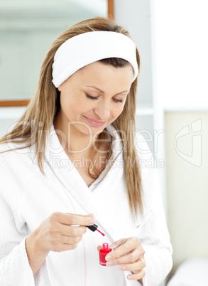 Bright caucasian woman varnishing her fingernails in the bathroo