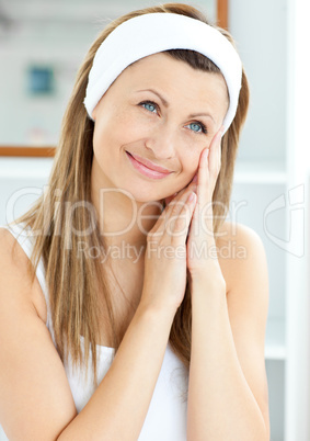 Young woman putting creme on her face wearing a headband in the