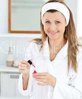 Positive caucasian woman varnishing her fingernails in the bathr