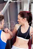 Cute athletic woman using a bench press with her coach