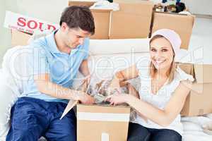 Joyful caucasian couple unpacking boxes with glasses