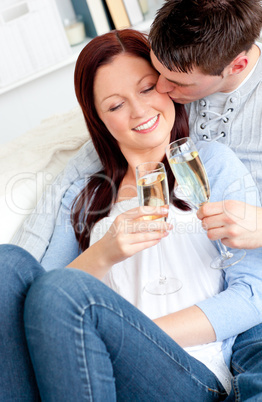 Attractive couple drinking champagne lying on the sofa