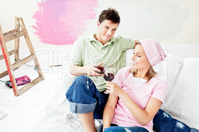 Delighted caucasian couple lying on a sofa and drinking wine aft