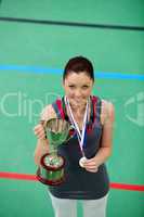 Smiling young woman holding a trophee and a medal