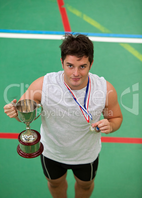 Happy young man holding a trophee and a medal