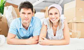 Smiling couple lying on the floor after unpacking boxes