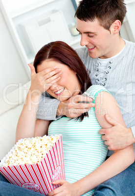 Charming couple lying on the sofa with popcorn and remote