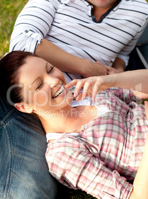 Glad couple of students sitting on grass and smiling at the came