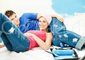 Happy young couple relaxing after painting a room