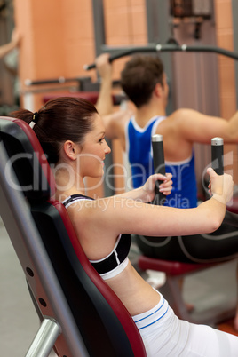 Radiant athletic woman using a shoulder press