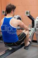Athletic caucasian man using a rower