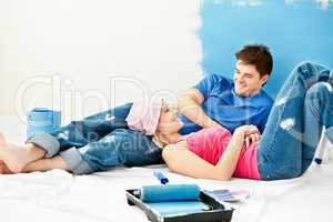 Happy couple relaxing after painting a room