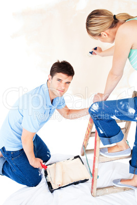 Beautiful caucasian couple painting a room