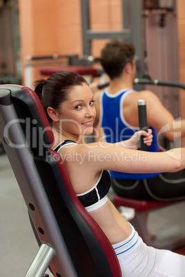 Pretty athletic woman using a shoulder press