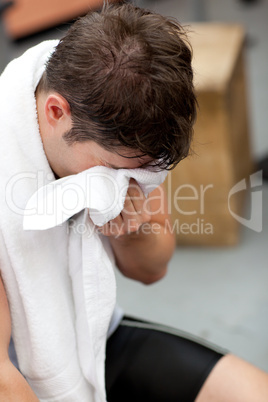 Harrassed athletic man standing with a towel