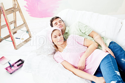 Positive caucasian couple sleeping on a sofa after painting a ro