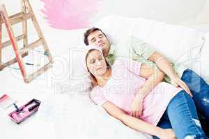 Positive caucasian couple sleeping on a sofa after painting a ro