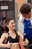 Joyful athletic woman using a shoulder press with her coach
