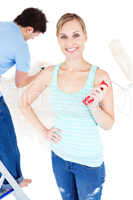 Merry young couple painting a room