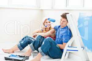 Charming couple relaxing after painting a room