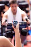 Caucasian woman holding a chronometer and man doing physical exe