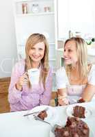 Happy female friends eating a chocolate cake and drinking in the
