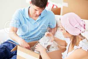 Concentrated young couple unpacking boxes with glasses