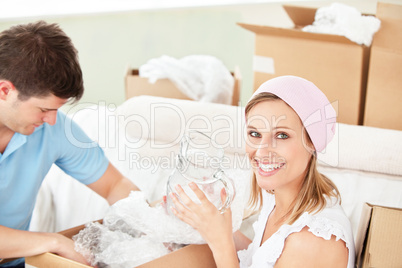 Delighted young couple unpacking boxes with glasses
