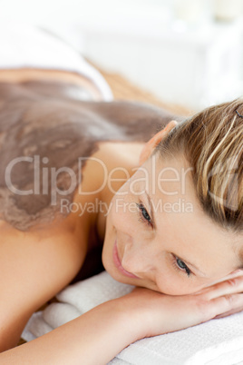 Portrait of a woman lying on a massage table with mud on her bac