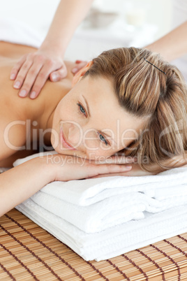 Cute young woman having a back massage in a spa center