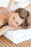 Cute young woman having a back massage in a spa center