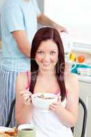 Charming woman eating her breakfast at home holding a bowl of ce