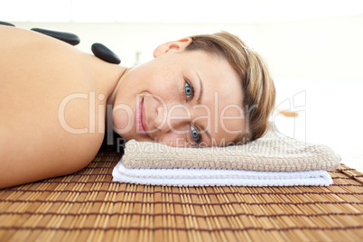 Portrait of a young woman lying on a massage table with hot ston