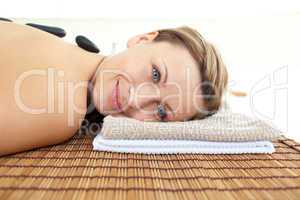Portrait of a young woman lying on a massage table with hot ston