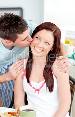 Attentive boyfriend kissing his girlfriend at her cheek during b