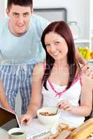 Smiling couple using a laptop while breakfast at home