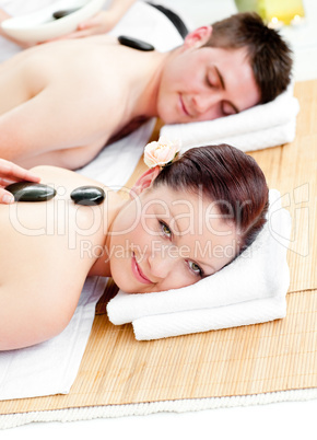 Charming young couple receiving a back massage with hot stones