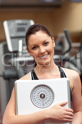 Cute woman holding a scales and smiling at the camera