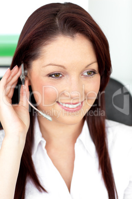 Positive young businesswoman sitting at her desk and wearing ear