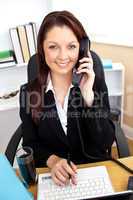 Self-assured businesswoman talking on phone and using her laptop