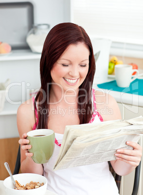 Bright woman eating cereals while reading newspaper in the kitch