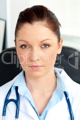 Serious female doctor smiling at the camera sitting