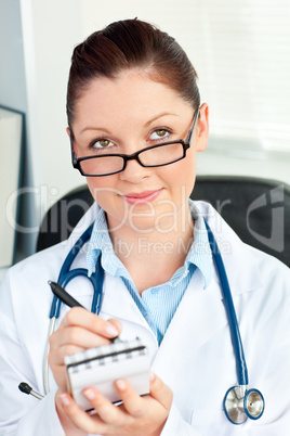 Thoughtful female doctor smiling at the camera holding a notepad