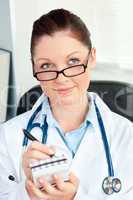 Thoughtful female doctor smiling at the camera holding a notepad