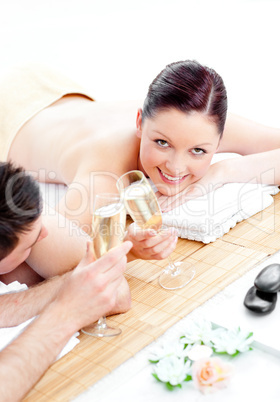 Caucasian young couple lying on a massage table and drinking cha