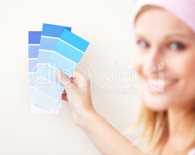 Attractive young woman choosing color for painting a room