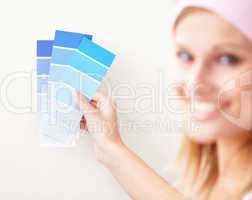 Attractive young woman choosing color for painting a room