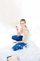 Cheerful young woman painting a room in her new house