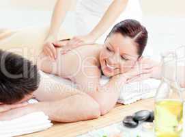 Glowing young couple receiving a back massage