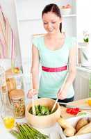 Glowing young woman preparing salad at home